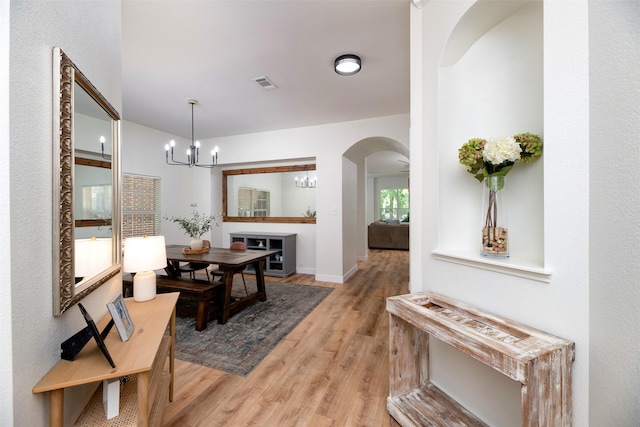 3945 Ringdove Way, Fort Worth, TX 76262 - corridor featuring light wood-type flooring, arched walkways, a chandelier, and baseboards
