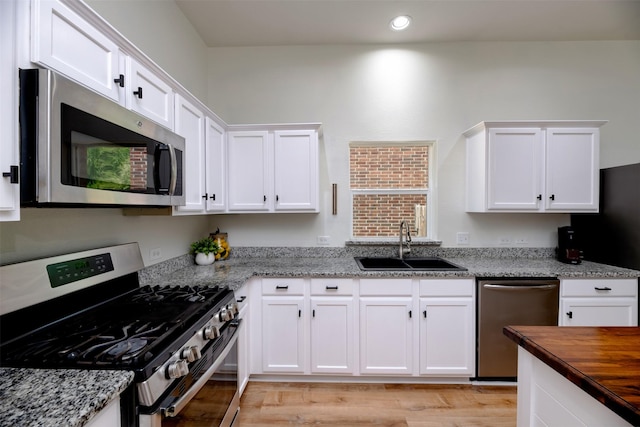 3945 Ringdove Way, Fort Worth, TX 76262 - kitchen with appliances with stainless steel finishes, a sink, white cabinetry, light wood-type flooring, and recessed lighting