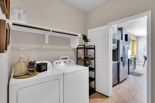 washroom featuring light tile patterned floors, washing machine and dryer, and laundry area