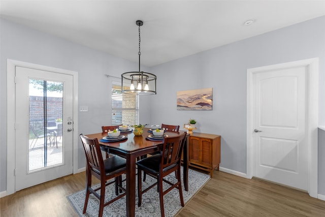 dining area with light wood-style flooring, baseboards, and an inviting chandelier