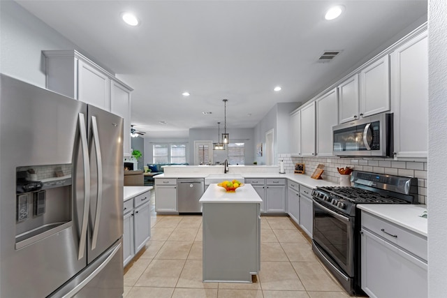kitchen featuring a peninsula, appliances with stainless steel finishes, light countertops, and backsplash