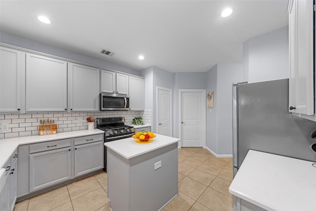 kitchen featuring tasteful backsplash, visible vents, light countertops, appliances with stainless steel finishes, and a kitchen island