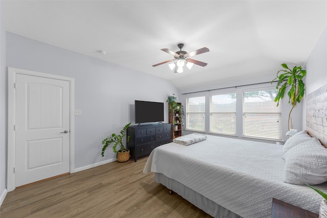 bedroom with baseboards, a ceiling fan, vaulted ceiling, and wood finished floors