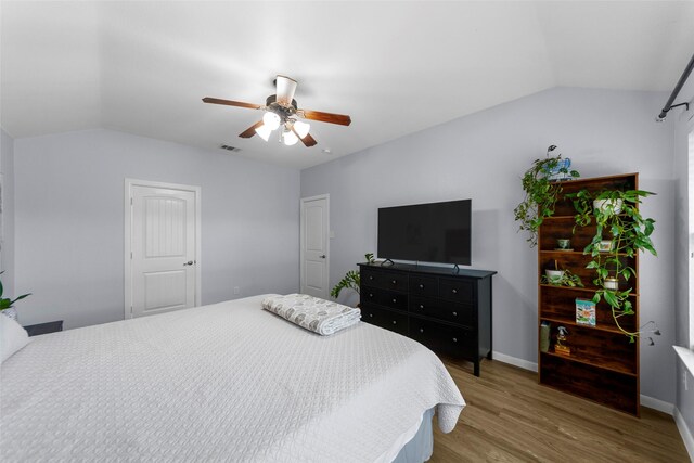 bedroom with visible vents, ceiling fan, wood finished floors, and vaulted ceiling
