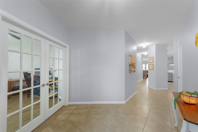 hall with french doors, baseboards, and light tile patterned flooring