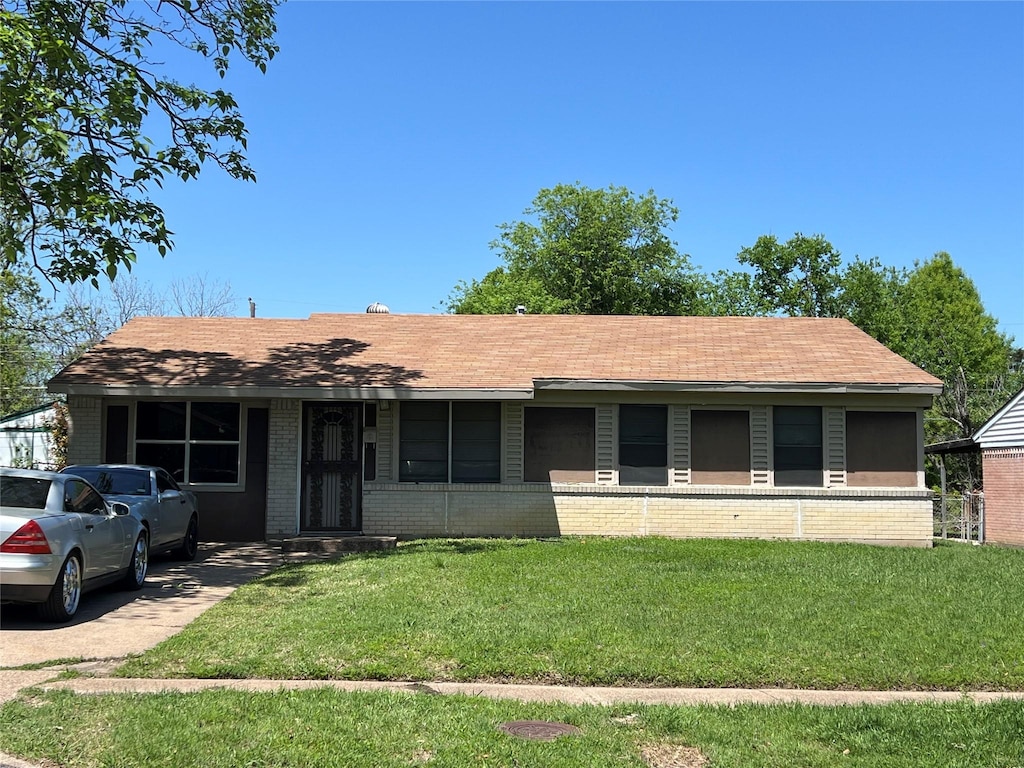ranch-style home featuring a front yard, brick siding, and a shingled roof