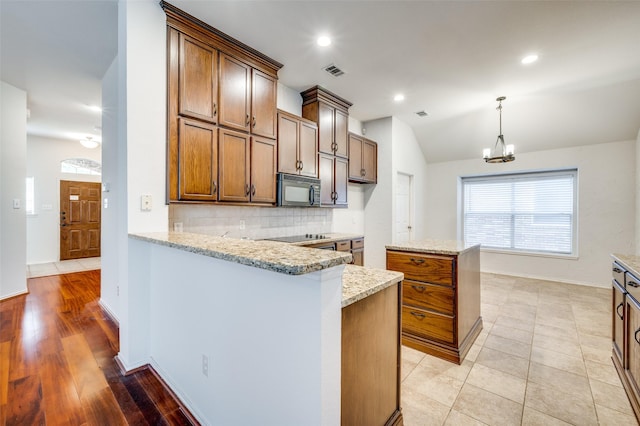 9133 Wichita Trl, Frisco, TX 75033 - kitchen with vaulted ceiling, visible vents, decorative backsplash, black appliances, and hanging light fixtures