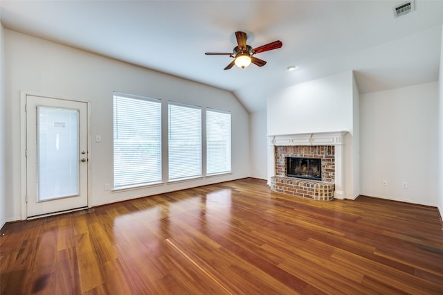 9133 Wichita Trl, Frisco, TX 75033 - unfurnished living room featuring vaulted ceiling, visible vents, a ceiling fan, wood finished floors, and a brick fireplace