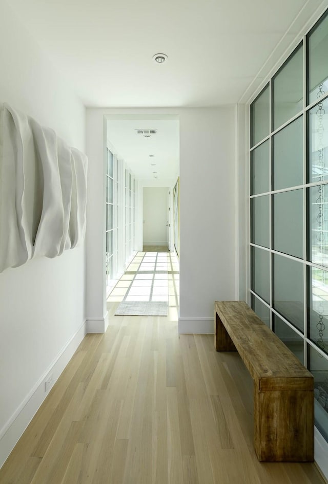 hallway featuring wood finished floors, baseboards, and visible vents