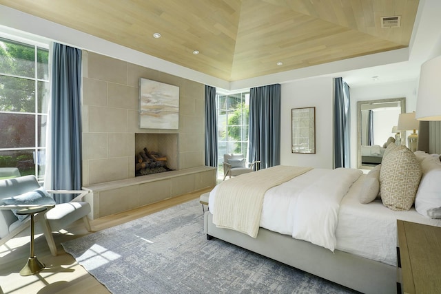 bedroom featuring wood finished floors, a fireplace, multiple windows, and visible vents