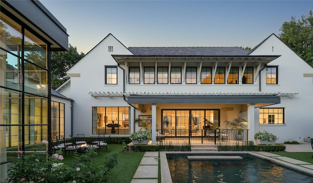 rear view of house featuring an outdoor pool, a patio area, and stucco siding