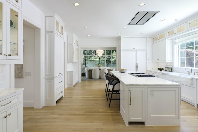 kitchen with a kitchen breakfast bar, recessed lighting, gas cooktop, white cabinets, and a sink