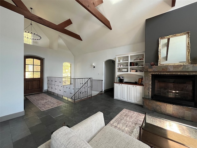 living area featuring a glass covered fireplace, baseboards, beamed ceiling, high vaulted ceiling, and arched walkways