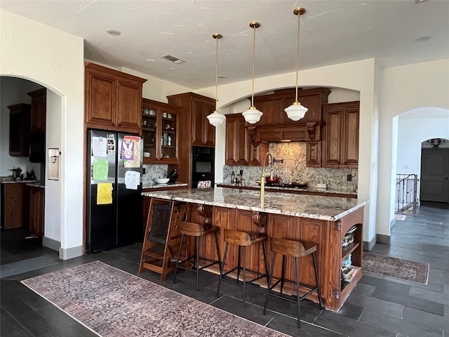 kitchen featuring glass insert cabinets, tasteful backsplash, visible vents, black appliances, and a large island