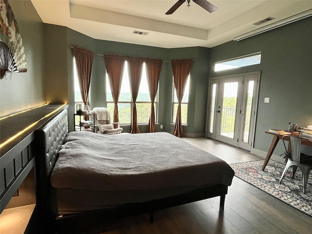 bedroom with visible vents, access to outside, a tray ceiling, and light wood-style floors
