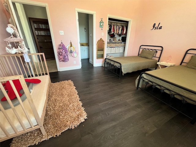 bedroom featuring ensuite bathroom, baseboards, and wood finished floors