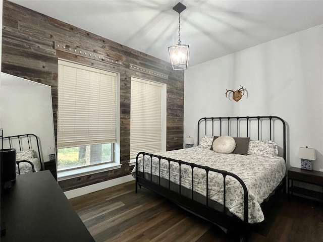 bedroom featuring a chandelier, wood finished floors, wooden walls, and baseboards