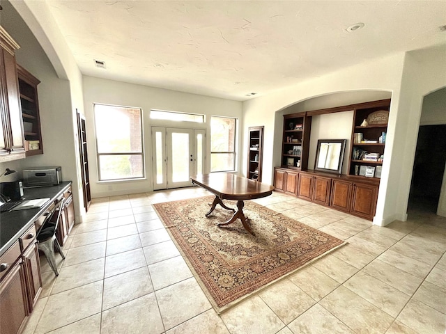 living room with french doors, visible vents, built in shelves, and light tile patterned floors