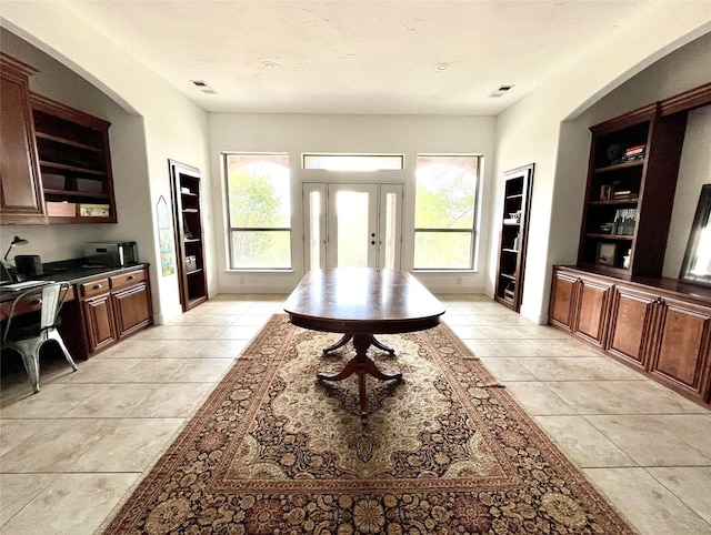 interior space with a healthy amount of sunlight, light tile patterned flooring, and visible vents