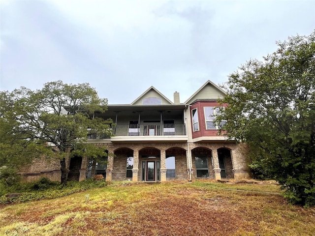 view of front facade featuring brick siding and a balcony