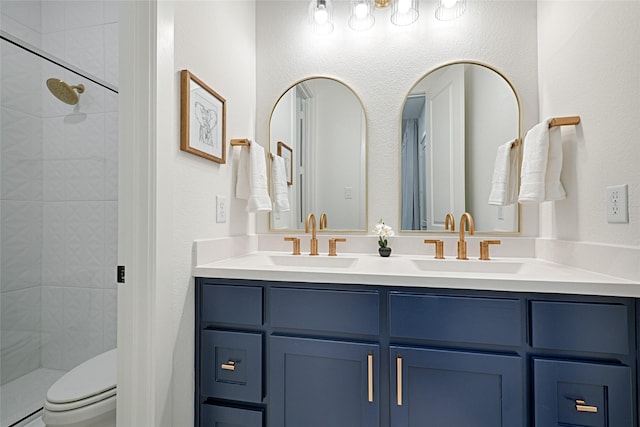 bathroom with a sink, toilet, double vanity, and tiled shower