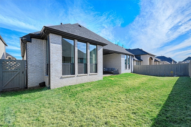 rear view of house featuring a yard, brick siding, and a fenced backyard