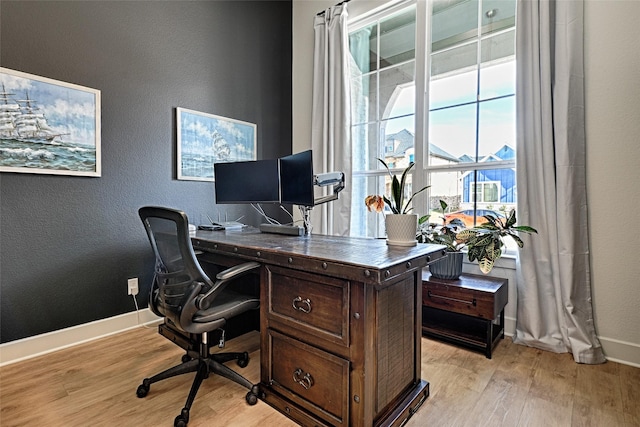 office area with a textured wall, light wood-style flooring, and baseboards