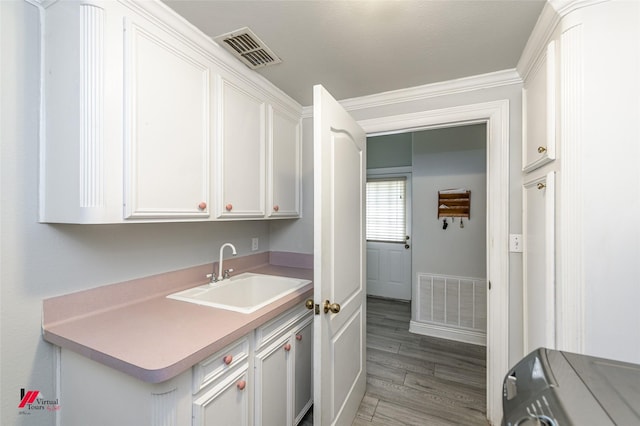 1231 Whitehall Dr, Bossier City, LA 71112 - clothes washing area featuring light wood-style flooring, a sink, cabinet space, and visible vents