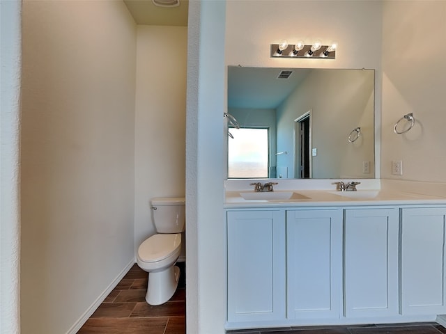 bathroom featuring visible vents, toilet, a sink, wood tiled floor, and double vanity