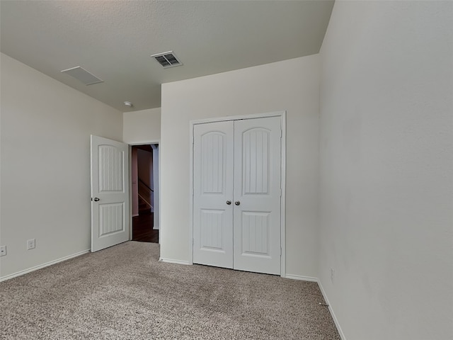 unfurnished bedroom featuring carpet floors, baseboards, a closet, and visible vents