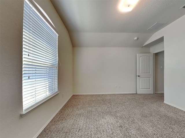 spare room featuring visible vents, baseboards, carpet, and lofted ceiling