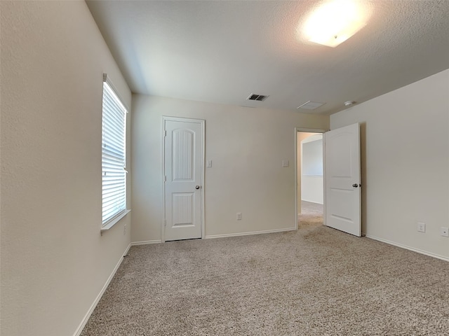 unfurnished room with a wealth of natural light, carpet flooring, visible vents, and baseboards