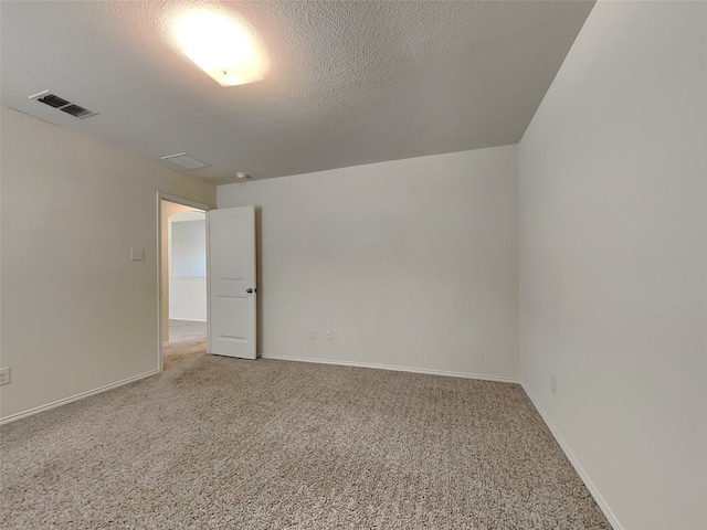 spare room with a textured ceiling, light colored carpet, baseboards, and visible vents