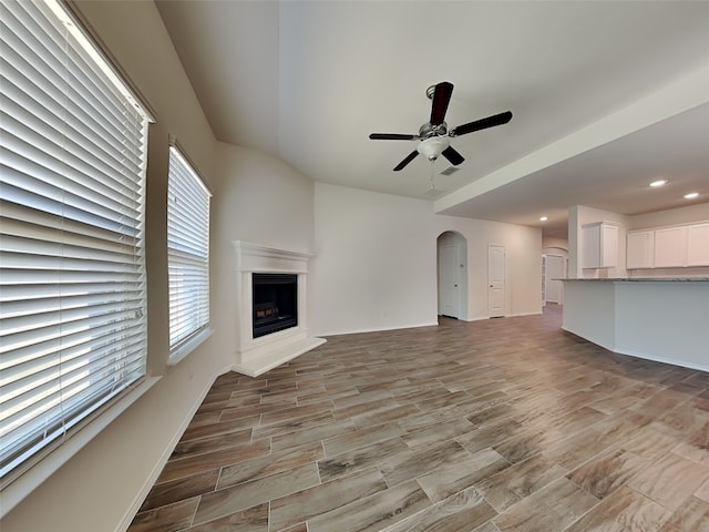 unfurnished living room with recessed lighting, plenty of natural light, arched walkways, and a ceiling fan