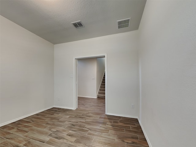 unfurnished room featuring stairs, visible vents, baseboards, and wood finish floors