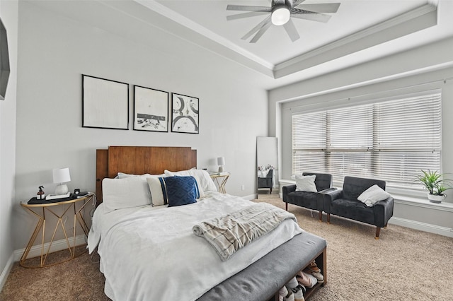 carpeted bedroom with a raised ceiling, crown molding, ceiling fan, and baseboards