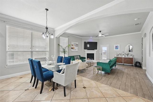 dining area featuring light tile patterned floors, a fireplace, arched walkways, a ceiling fan, and baseboards