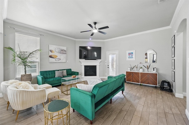 living area featuring ornamental molding, ceiling fan, light wood finished floors, and a wealth of natural light