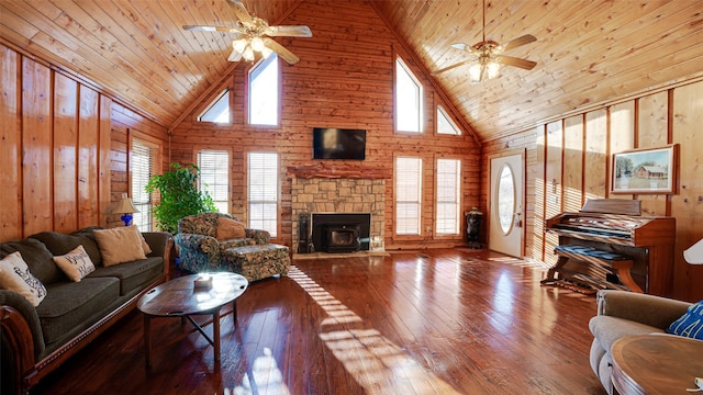 living area featuring high vaulted ceiling, wood walls, wooden ceiling, and ceiling fan