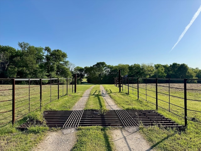surrounding community featuring a rural view, fence, and a lawn