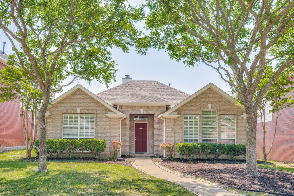 single story home with roof with shingles, a chimney, a front lawn, and brick siding