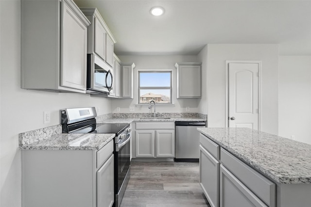 14203 Riata Ln, Dallas, TX 75253 - kitchen with a sink, appliances with stainless steel finishes, light wood-style floors, light stone countertops, and a kitchen island