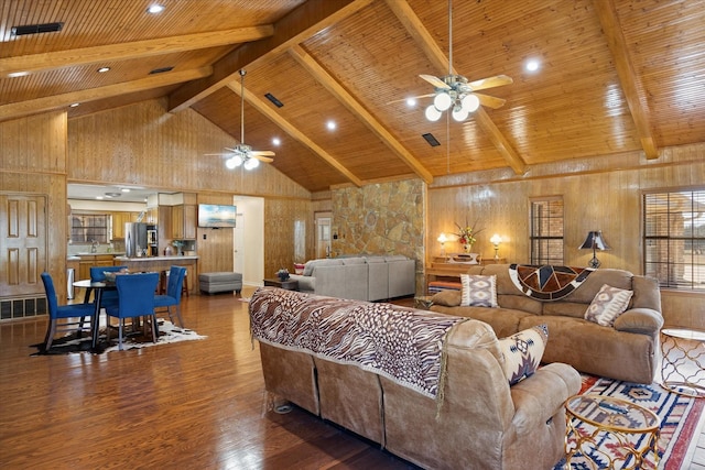 living area featuring beamed ceiling, visible vents, a ceiling fan, and wood finished floors
