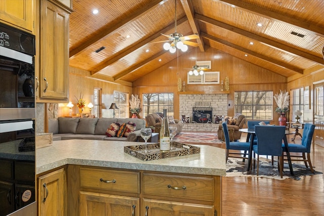 kitchen featuring open floor plan, a ceiling fan, wood finished floors, and a brick fireplace