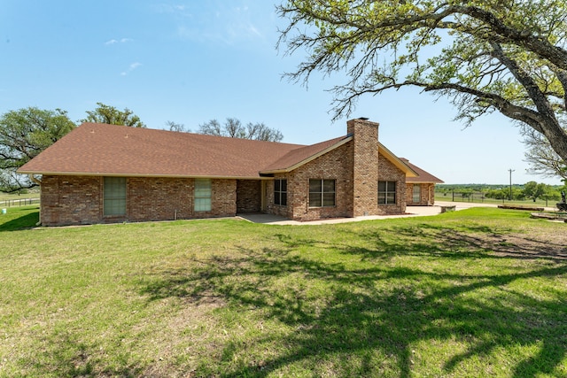 view of front of house with a shingled roof, brick siding, a chimney, and a front lawn