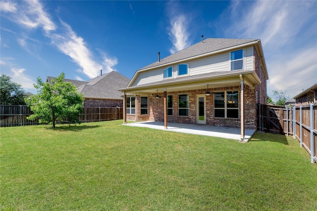 rear view of property with a fenced backyard, brick siding, a yard, and ceiling fan