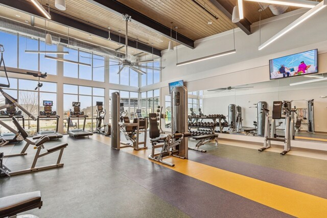 exercise room featuring wood ceiling, a ceiling fan, and a high ceiling