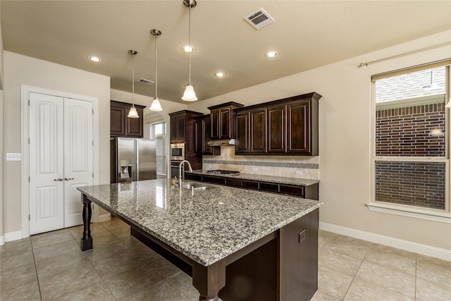 kitchen with dark brown cabinetry, stainless steel appliances, visible vents, and a sink