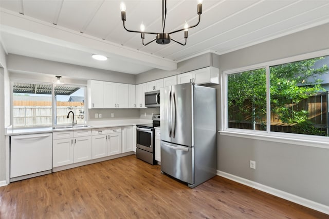1001 Roaring Springs Dr, Allen, TX 75002 - kitchen featuring appliances with stainless steel finishes, a sink, baseboards, white cabinetry, and healthy amount of natural light