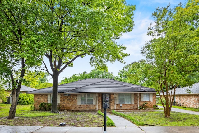 ranch-style home featuring brick siding and a front lawn